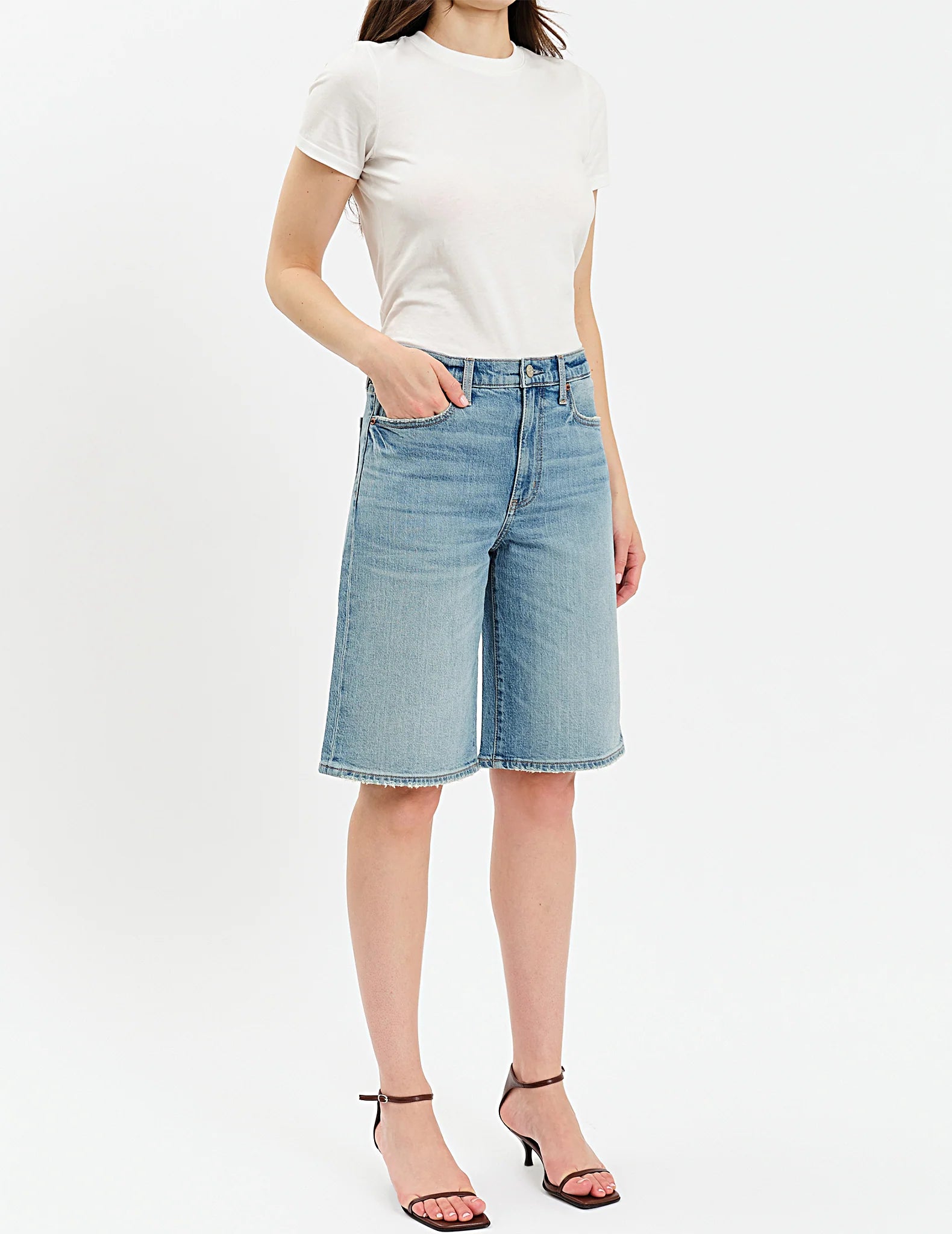 Person wearing a white t-shirt and light blue denim shorts on a white background