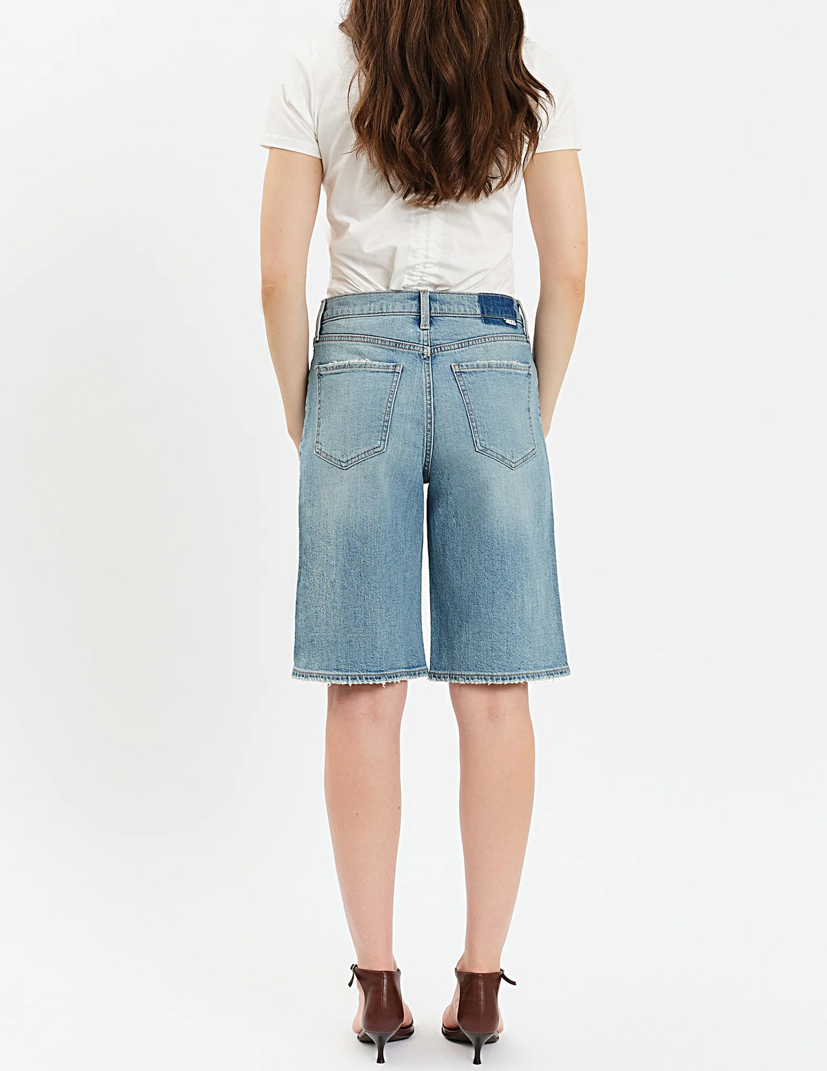 Person wearing blue denim shorts on a white background