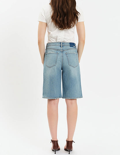Person wearing blue denim shorts on a white background