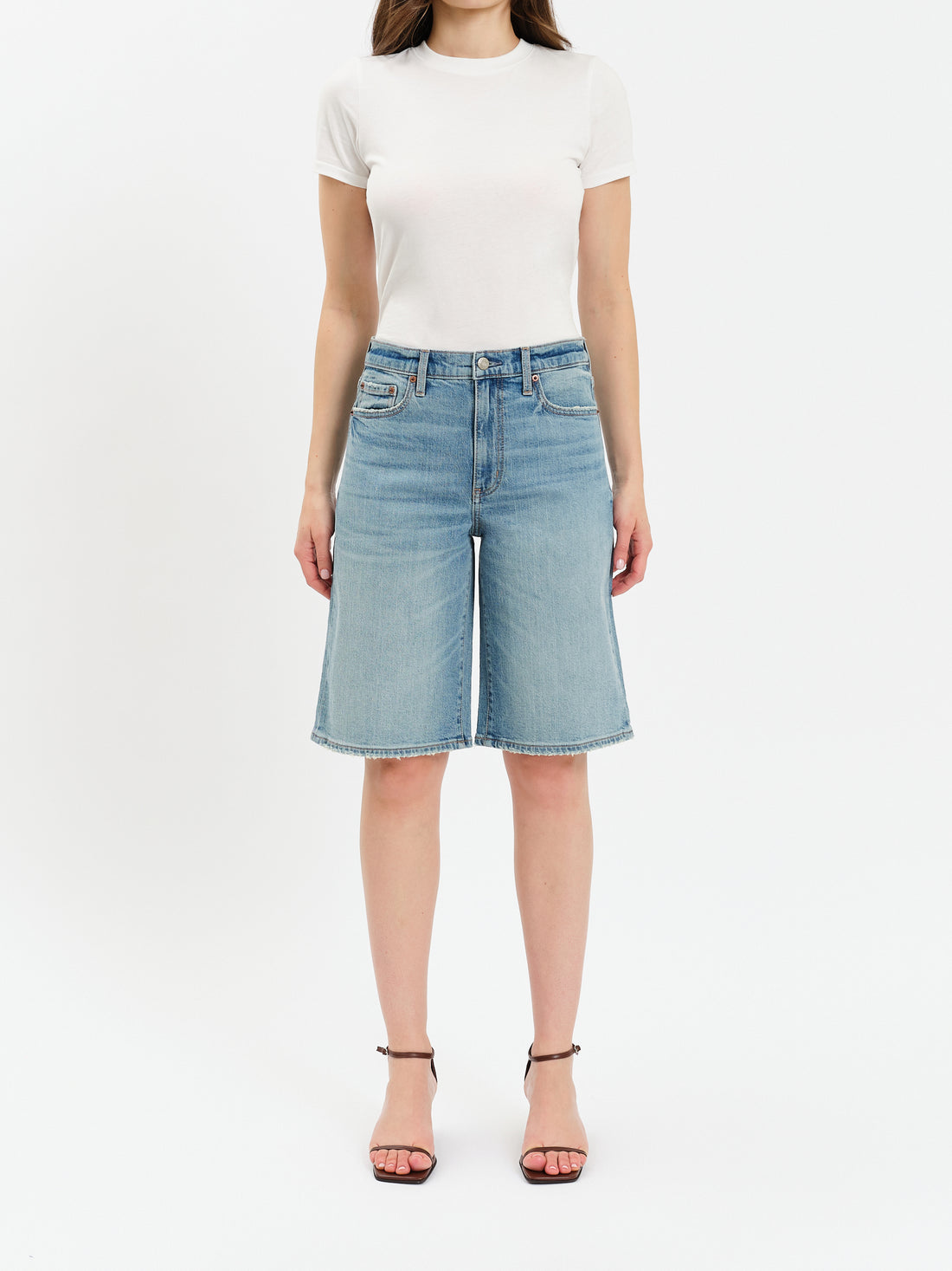 Person wearing a white t-shirt and light blue denim shorts on a white background