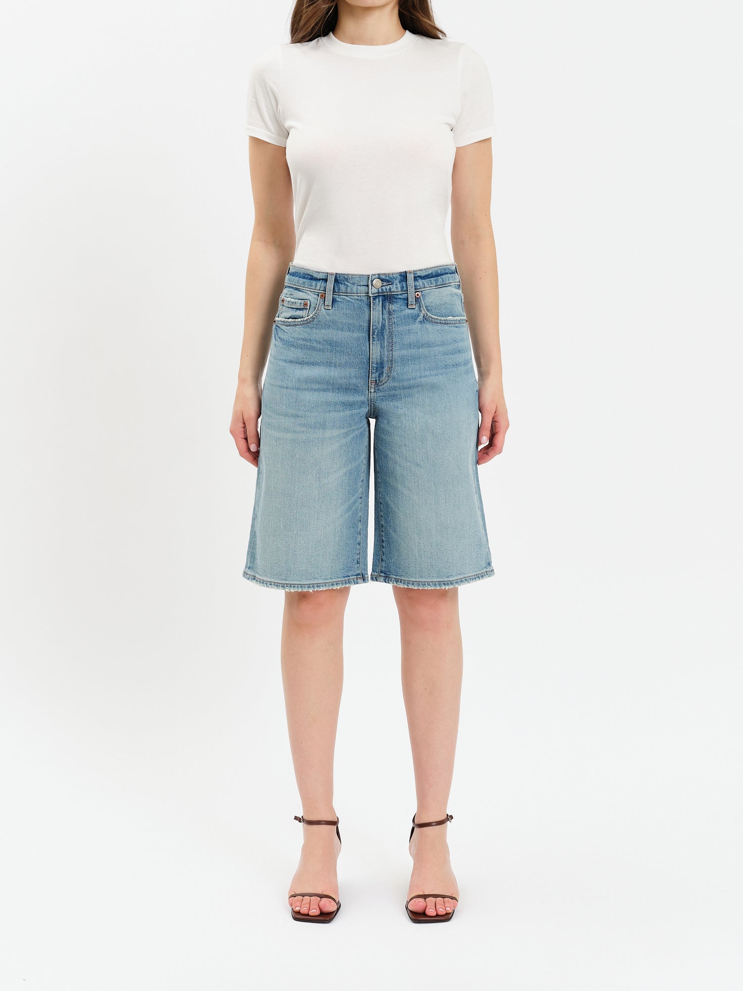 Person wearing a white t-shirt and light blue denim shorts on a white background