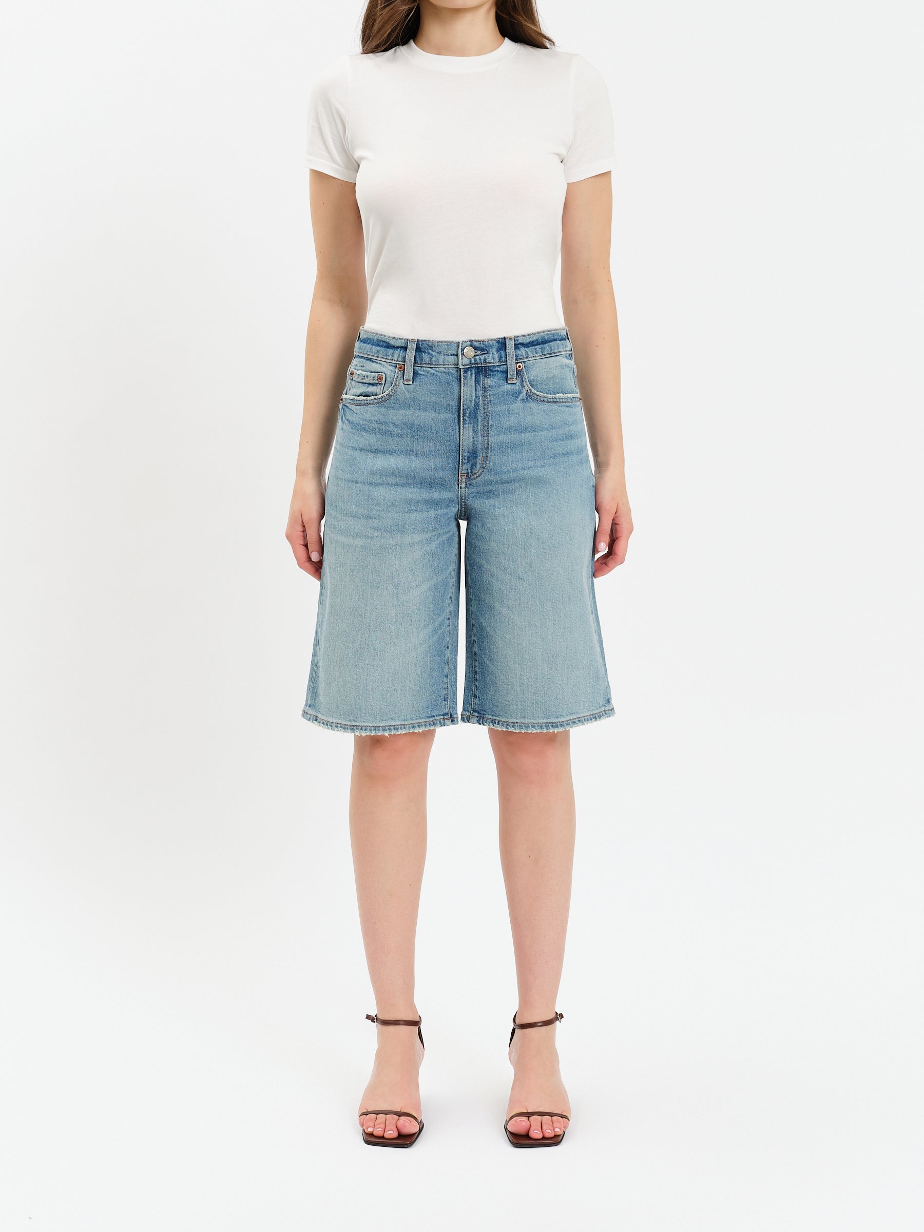 Person wearing a white t-shirt and light blue denim shorts on a white background