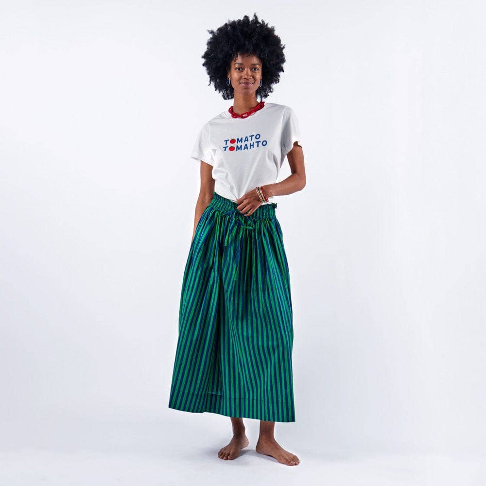 Woman wearing a white t-shirt with text and a green striped skirt on a white background